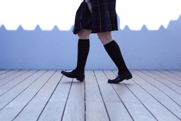 Low Section Of Schoolgirl Walking On Footpath