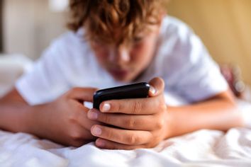 Teenager boy is using smartphone at home in bed