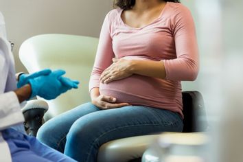 Doctor with protective gloves prepares to examine a pregnant woman