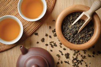 Oolong teaTea leaves spilling out from wooden bowl, near freshly brewed Oolong tea