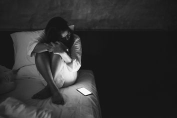 Sad woman staring at phone bed
