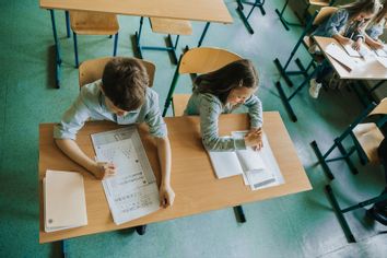 Overhead view on schoolboy and schoolgirl at school desk
