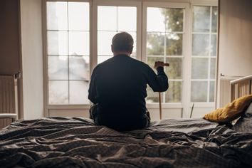 Lonely old man sitting on bed