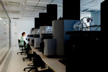 A female scientist sits amid large machinery in a leading medical research center.