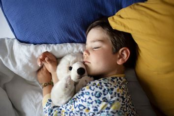  4 year old little boy sleeping with his cuddly toy in his bed