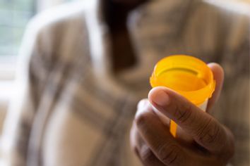 Woman holding open prescription pill bottle