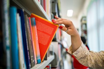 Woman's hand picking a book from a bookshelf