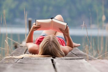 Woman lying and reading book on a jetty