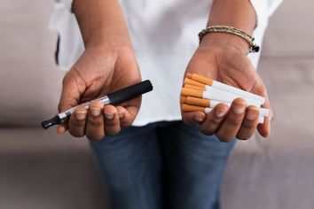 Hands holding vape and cigarettes