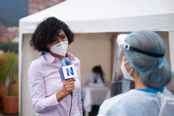 Journalist interviewing a healthcare worker working at a COVID-19 vaccination stand