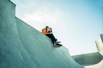 Two teenage girls in a skatepark, sharing a cell phone