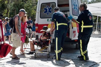 At the Acropolis ancient hill, medics help woman who has passed out from the heat during a heat wave on July 20, 2023 in Athens, Greece.