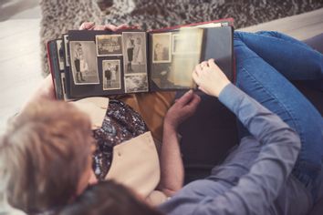 Young woman on sofa with grandmother looking at photo album
