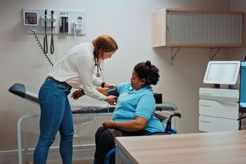 Doctor taking patient blood pressure in hospital examination room.
