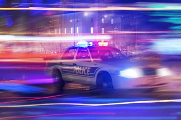 Police car speeding through traffic at night time