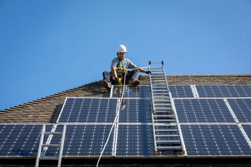 Maintenance worker installing solar panels to house