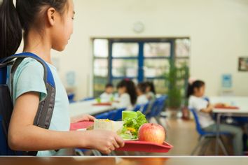 School girl holding food tray in school cafeteria