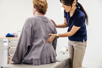 Female osteopath examining senior woman's back at clinic