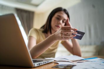 Young woman stressed worried about finances, looking at credit card