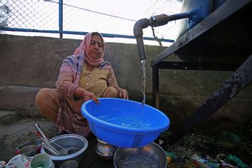 Woman utilizing water supply station Kashmir India