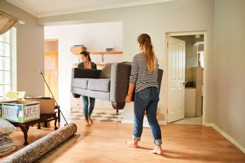 Women roommates friends moving couch into apartment