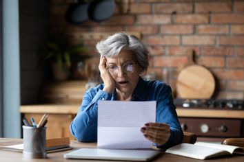 Mature woman looking at bills in shock