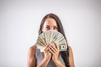 Woman holding a fan of US dollars looking at money finance