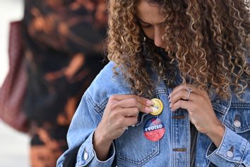 young woman attaches a pin to her jacket after voting election