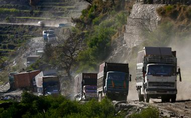 A convoy of Afghan trucks carrying wheat and US military supplies travels through Kunar Province in eastern Afghanistan
