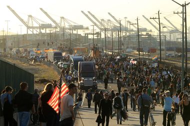 A demonstrator carries a U.S. flag as thousands of people converge on the Port of Oakland, California