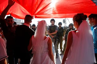 Palestinian couples face Israeli soldiers in a peaceful demonstration against Israel's separation wall before their wedding ceremony in the occupied West Bank, near Bethlehem, in 2009