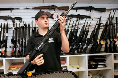 Salesman, Ryan Martinez inspects a new AR-10 at the "Ready Gunner" gun store in Provo