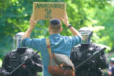 A left wing 'antifa' protester holds up a sign in front of riot police.