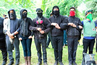 'Antifa' protesters link arms as they demonstrate at a rally