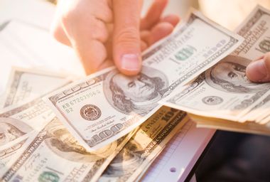 Hands counting us dollars with calculator and digital tablet