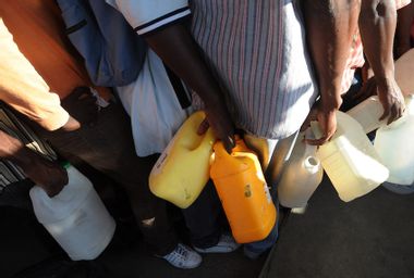 Haitian men queue for gasoline at a fuel