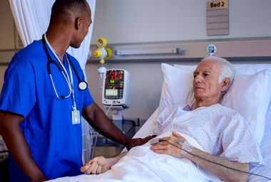 Male nurse doing routine checkup of senior patient in hospital room