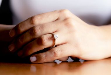 Close up of womans hand wearing an engagement ring.