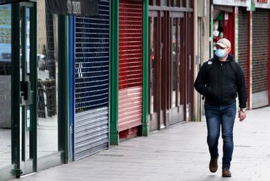 A man wearing a surgical face mask walks passed closed shops