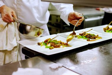Chef saucing dishes in restaurant kitchen