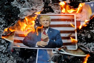 A portrait of US President Donald Trump burns during a demonstration