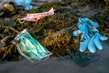Discarded used disposable medical mask floats in sea waters