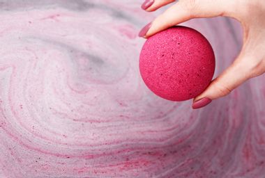 Woman's hand putting bath bomb into water
