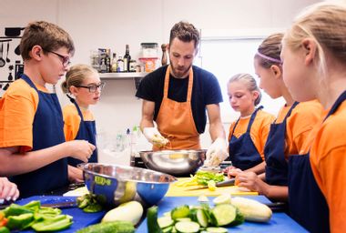 Teacher and students chopping vegetables in cooking class