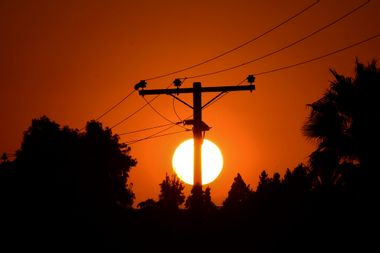 The sun sets behind power lines in Los Angeles, California