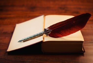 Feather quill pen on a vintage book