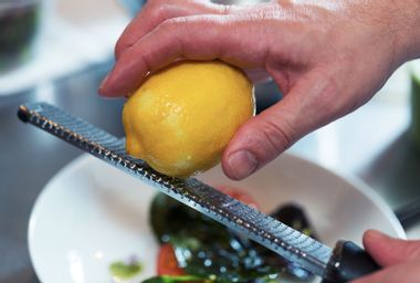 Zesting the peel of a lemon on a microplane grater