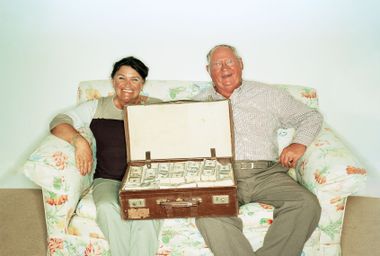 Mature couple on the sofa with a suitcase full of money
