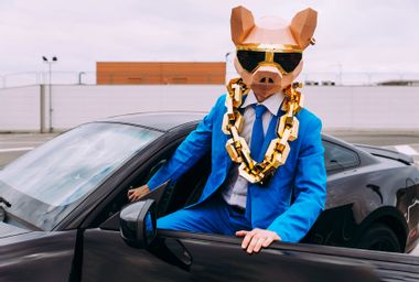 Man wearing animal mask and blue business suit getting in car