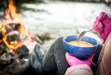 Woman Enjoying Food with Campfire